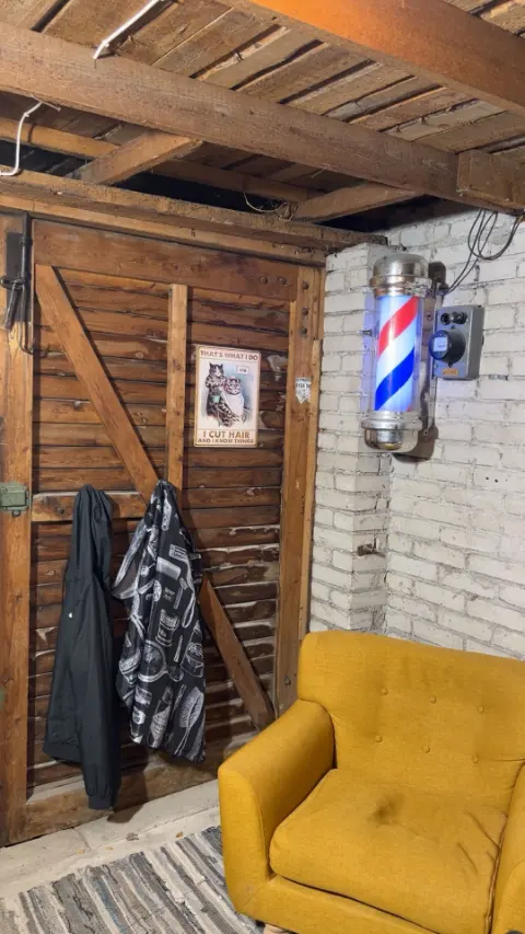 Puidust uks, seinal põlev barberipost ja kollane tugitool.